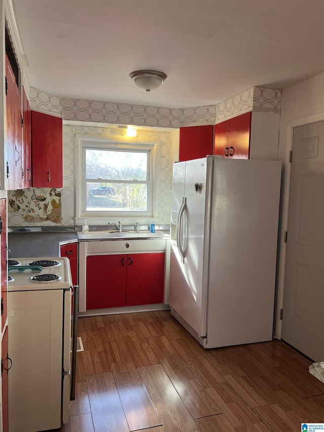 kitchen featuring red cabinetry, white appliances, light wood-style flooring, and wallpapered walls