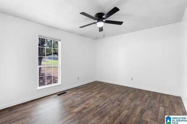 unfurnished room with dark wood-style flooring, visible vents, and baseboards