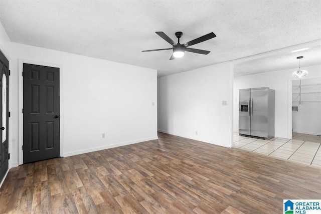 spare room featuring light wood-style floors, ceiling fan, and a textured ceiling