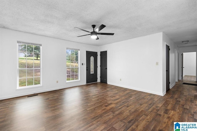 unfurnished room featuring dark wood-style flooring, visible vents, a ceiling fan, a textured ceiling, and baseboards