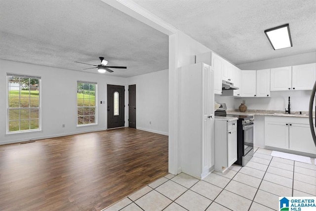 kitchen with under cabinet range hood, a sink, white cabinets, light countertops, and stainless steel electric range