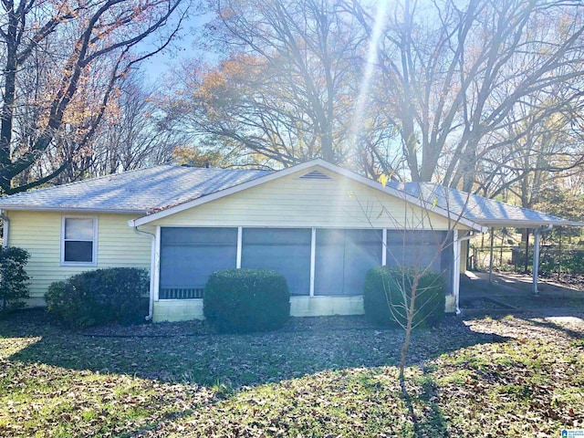 view of side of home with roof with shingles and a sunroom