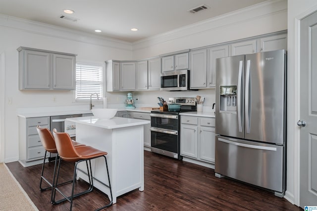 kitchen with a breakfast bar, visible vents, stainless steel appliances, and dark wood finished floors