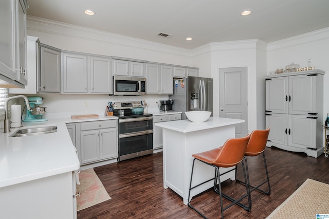 kitchen featuring a breakfast bar area, stainless steel appliances, a kitchen island, a sink, and crown molding