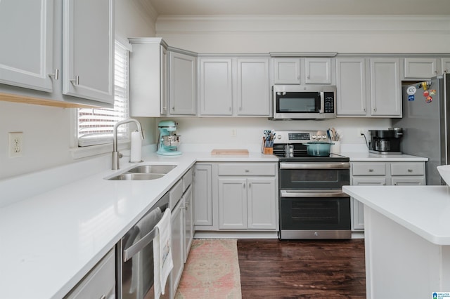 kitchen with dark wood-style floors, appliances with stainless steel finishes, light countertops, crown molding, and a sink