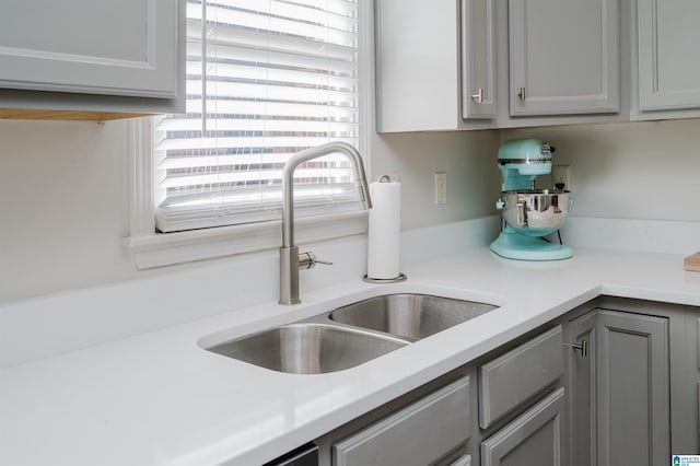 kitchen with light countertops, a sink, and gray cabinetry