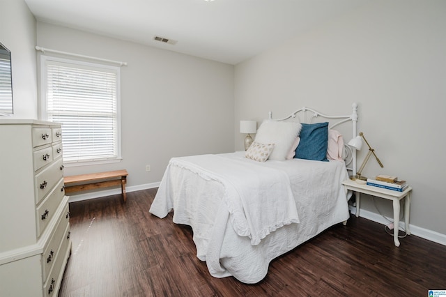 bedroom with dark wood-style flooring, visible vents, and baseboards