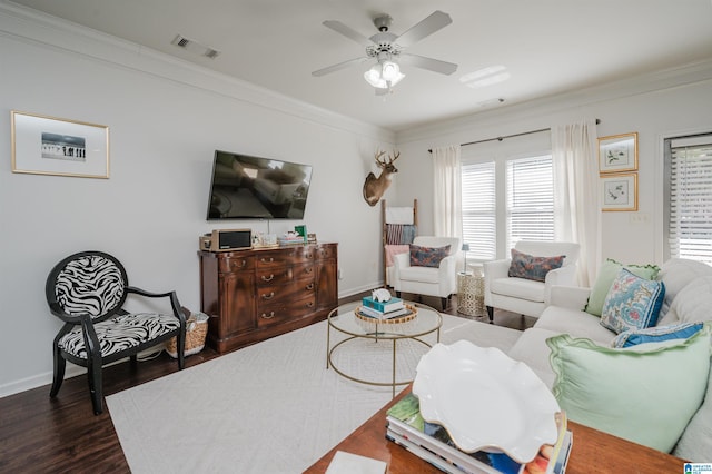 living room with baseboards, wood finished floors, visible vents, and crown molding