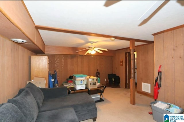 living area with carpet floors, visible vents, wooden walls, and a ceiling fan