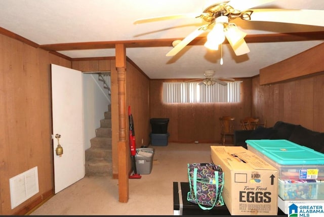 basement with stairs, wooden walls, visible vents, and a ceiling fan