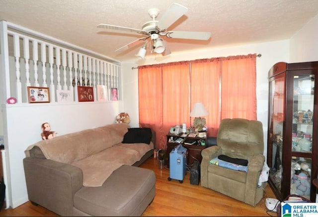 living area with ceiling fan, a textured ceiling, and wood finished floors