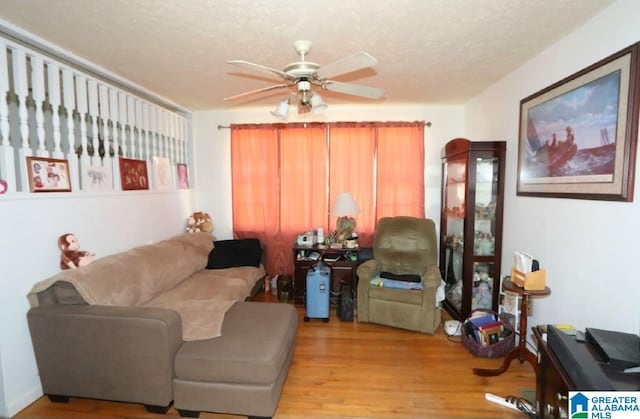 living area featuring a ceiling fan, a textured ceiling, and light wood finished floors