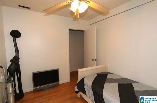 bedroom with ceiling fan, visible vents, and wood finished floors