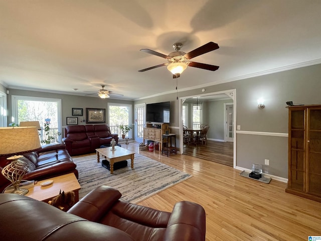 living area with light wood finished floors, baseboards, ornamental molding, and a wealth of natural light