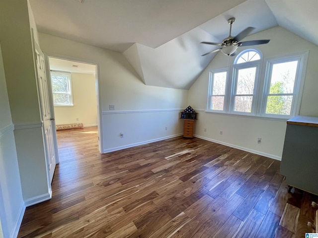 additional living space with dark wood-style floors, vaulted ceiling, baseboards, and a ceiling fan