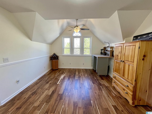 additional living space with dark wood-style floors, vaulted ceiling, baseboards, and a ceiling fan