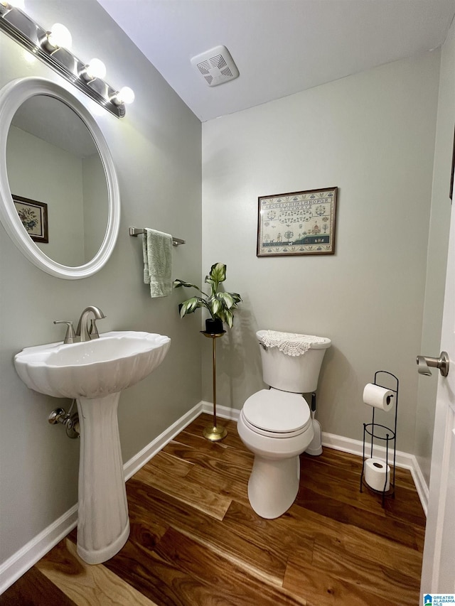 bathroom featuring toilet, baseboards, visible vents, and wood finished floors