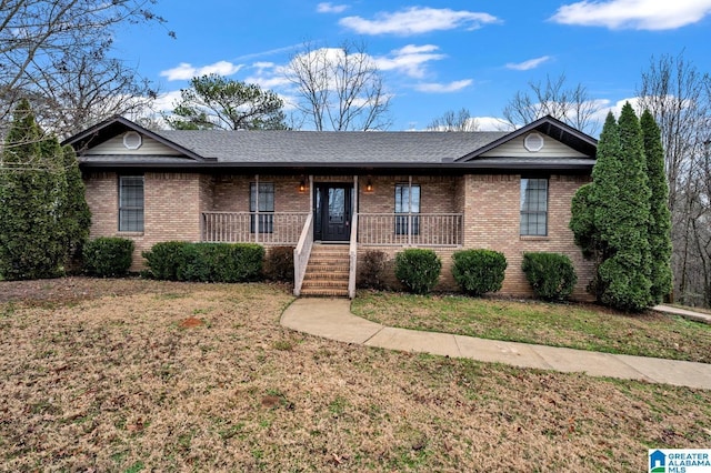 ranch-style house featuring a porch, a front yard, brick siding, and a shingled roof