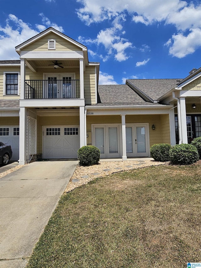 view of front of home with roof with shingles, an attached garage, ceiling fan, a balcony, and driveway