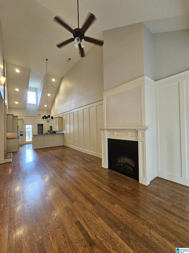 unfurnished living room featuring ceiling fan, recessed lighting, a decorative wall, a fireplace, and dark wood finished floors