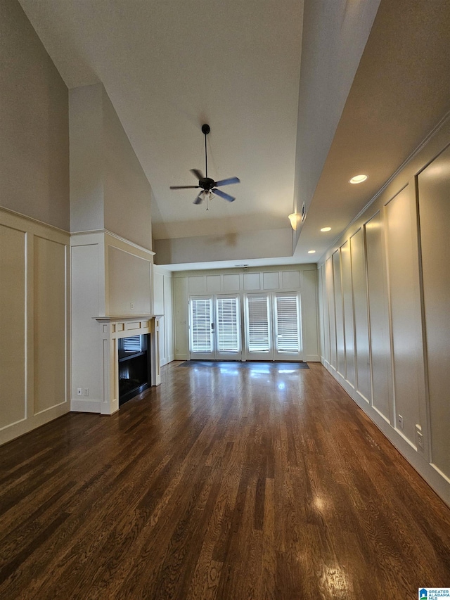 unfurnished living room with a ceiling fan, dark wood-type flooring, a fireplace, a decorative wall, and recessed lighting