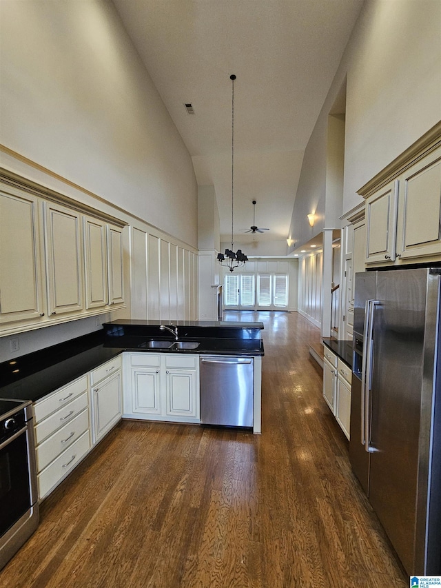 kitchen with dark wood-style floors, appliances with stainless steel finishes, open floor plan, a sink, and high vaulted ceiling