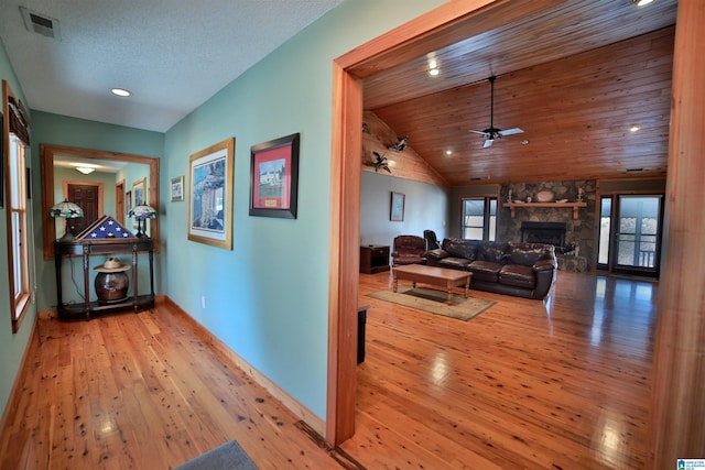 hallway with a textured ceiling, wooden ceiling, visible vents, light wood-style floors, and vaulted ceiling