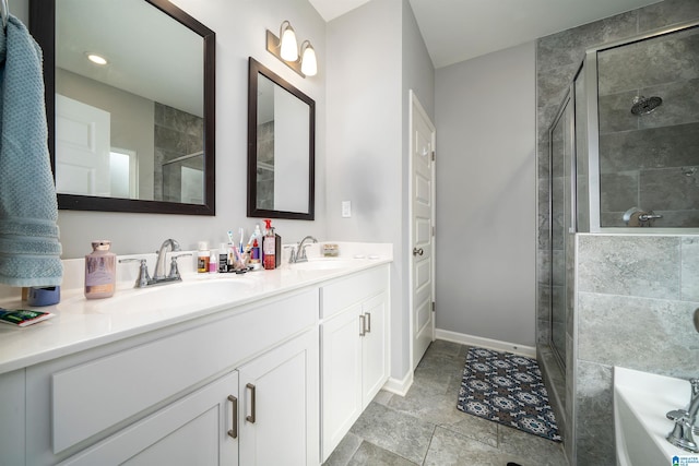 full bathroom with double vanity, a stall shower, baseboards, and a sink