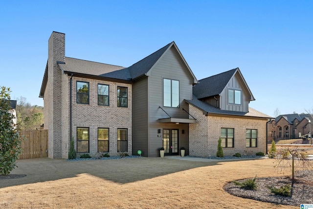 view of front of house featuring a chimney, fence, french doors, and brick siding