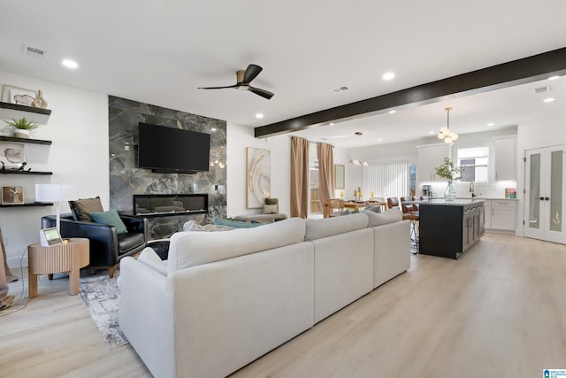 living room with light wood-style floors, visible vents, beamed ceiling, and recessed lighting