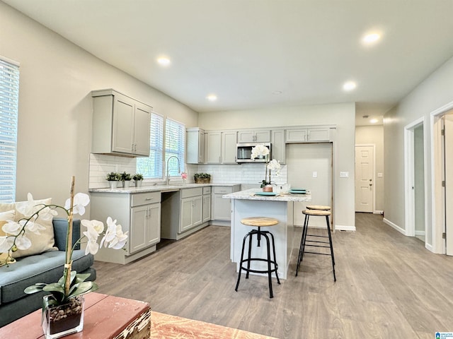 kitchen featuring light wood-style floors, stainless steel microwave, and gray cabinets