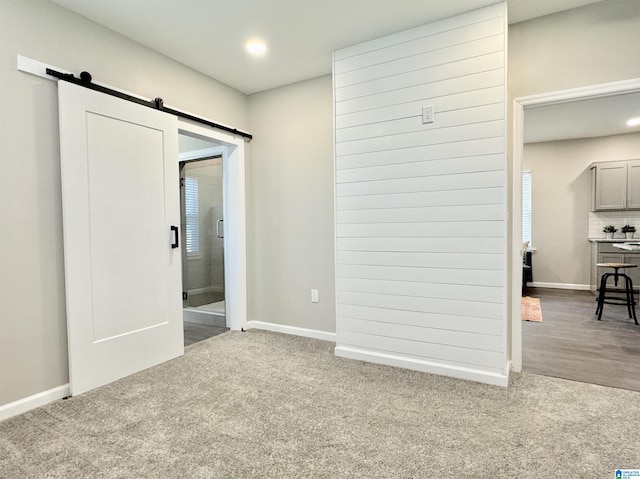 interior space featuring a barn door, recessed lighting, and baseboards