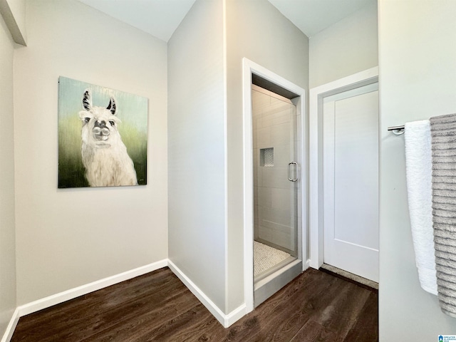 full bath featuring a stall shower, baseboards, and wood finished floors