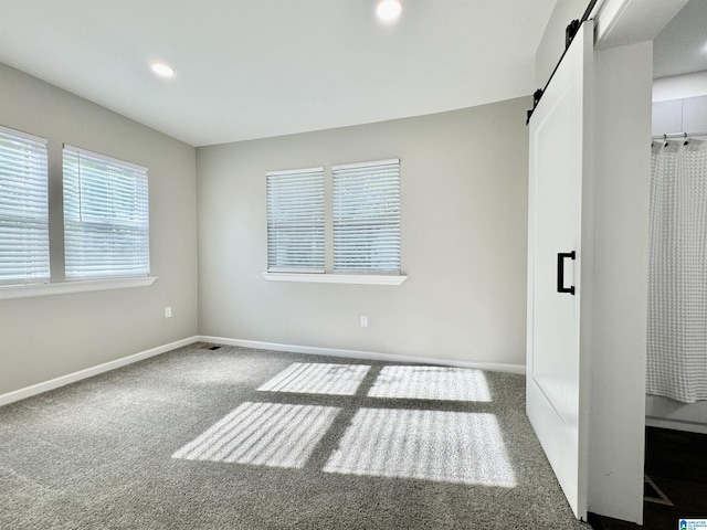 unfurnished bedroom with carpet floors, recessed lighting, baseboards, and a barn door