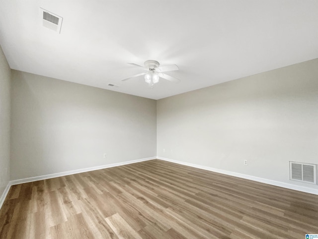 spare room featuring wood finished floors, visible vents, and a ceiling fan