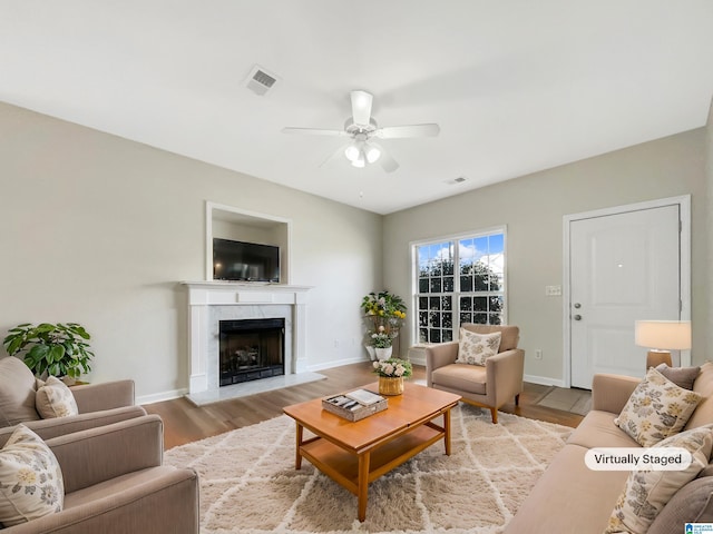 living area featuring a fireplace, visible vents, ceiling fan, wood finished floors, and baseboards