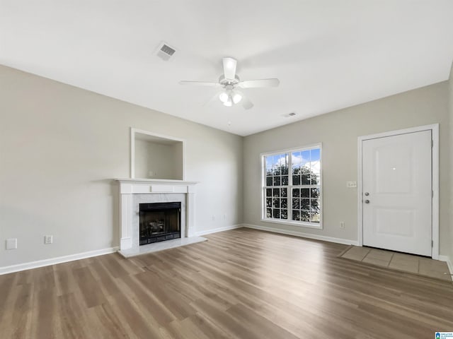 unfurnished living room featuring baseboards, visible vents, a ceiling fan, wood finished floors, and a fireplace