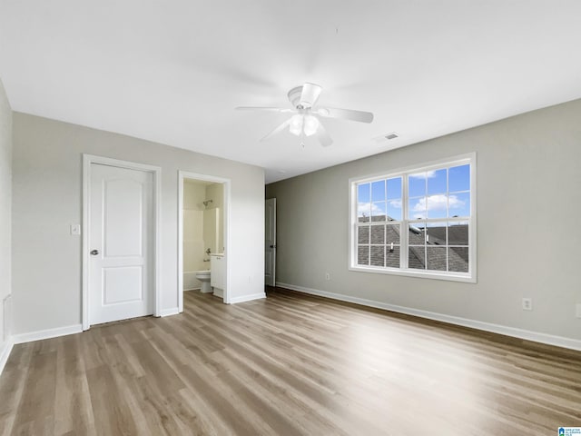 unfurnished bedroom featuring a ceiling fan, visible vents, baseboards, and wood finished floors