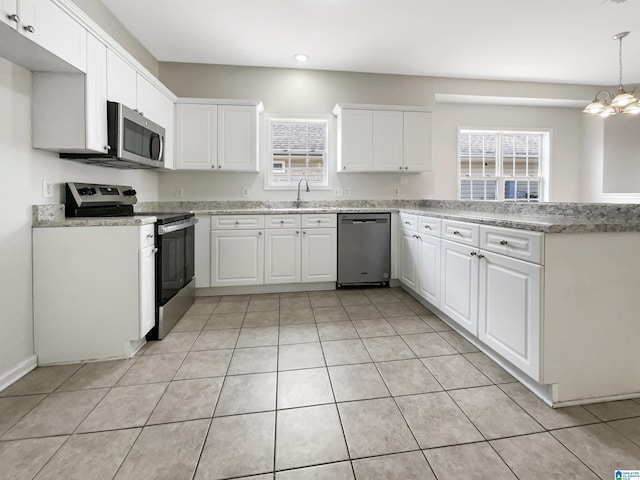 kitchen featuring appliances with stainless steel finishes, white cabinets, a healthy amount of sunlight, and a sink