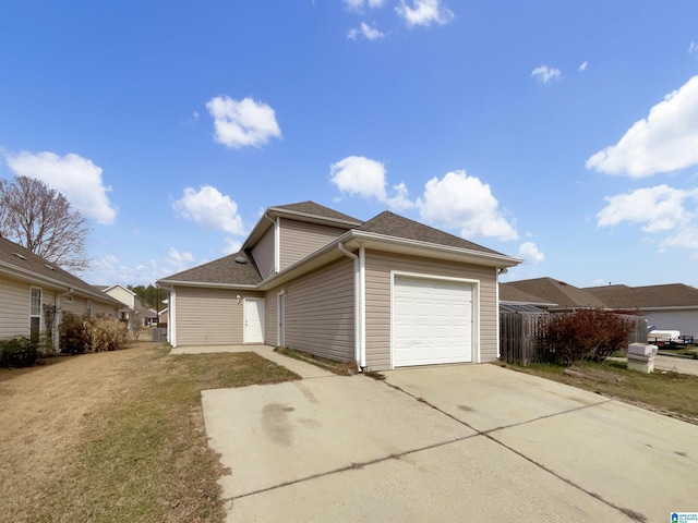 exterior space featuring a garage, a lawn, concrete driveway, and roof with shingles