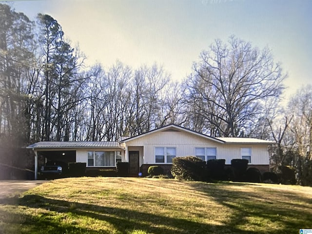 ranch-style house with concrete driveway, metal roof, an attached carport, a standing seam roof, and a front lawn