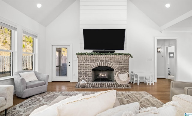 living room with a brick fireplace, recessed lighting, wood finished floors, and high vaulted ceiling