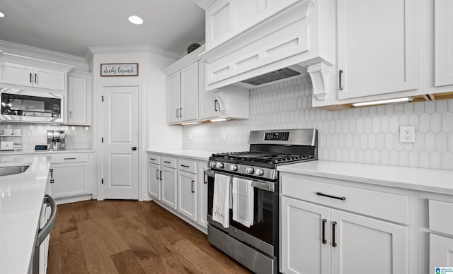 kitchen featuring ornamental molding, stainless steel appliances, light countertops, custom range hood, and white cabinets