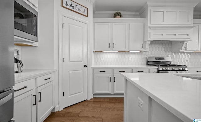 kitchen with white cabinetry, appliances with stainless steel finishes, dark wood-style flooring, and crown molding