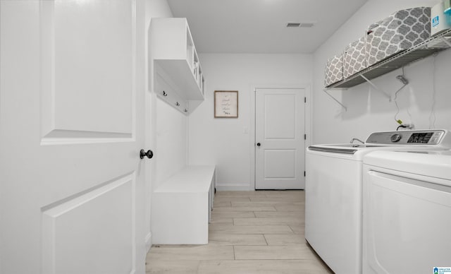 washroom with visible vents, wood tiled floor, laundry area, and washing machine and clothes dryer