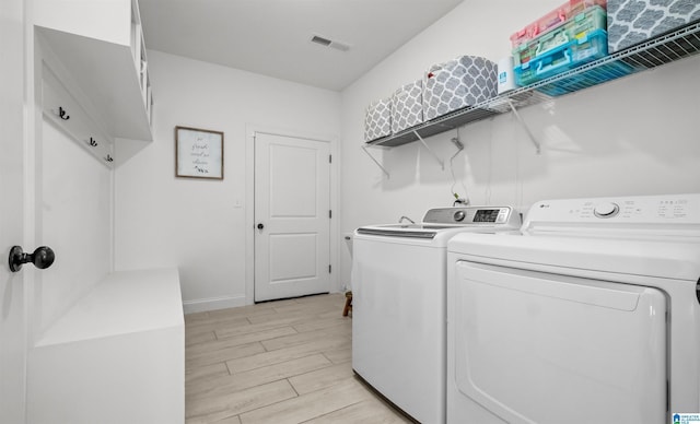 laundry room with baseboards, visible vents, wood tiled floor, laundry area, and separate washer and dryer