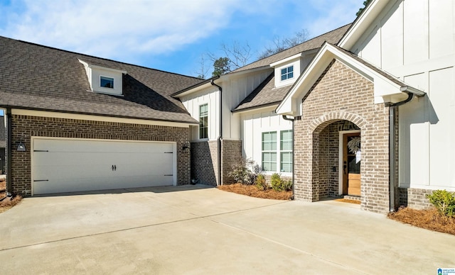 view of front of home with concrete driveway, brick siding, and board and batten siding