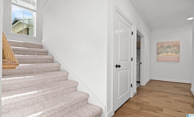 stairway featuring crown molding, wood finished floors, and baseboards