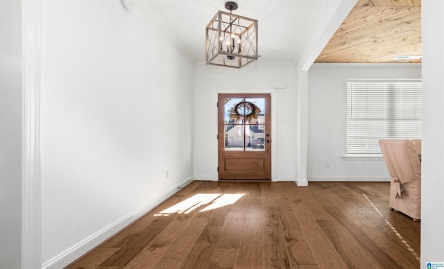 foyer entrance featuring crown molding, a notable chandelier, baseboards, and wood-type flooring