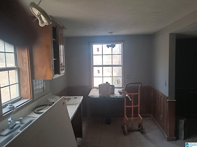 kitchen featuring light tile patterned floors, light countertops, and wainscoting